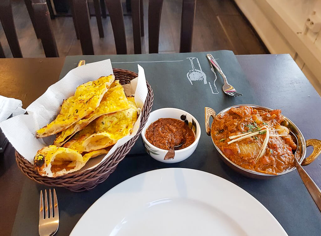 A basket of Indian roti bread is accompanied by a curry dish and a bowl of curry sauce.