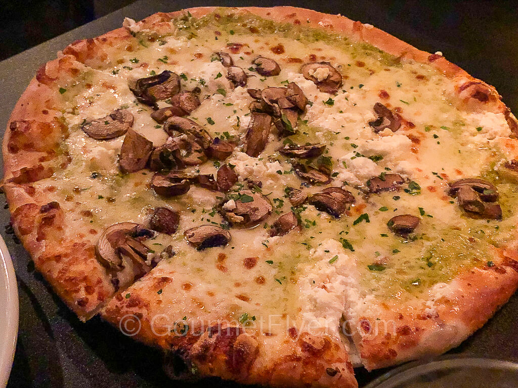 A pizza with slightly burnt edge is topped with melted cheese and a blend of various mushrooms.