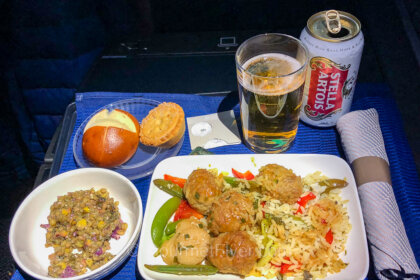 United's first-class menu features a dinner tray of Thai meatballs accompanied by a salad, roll, dessert, and a glass of beer.