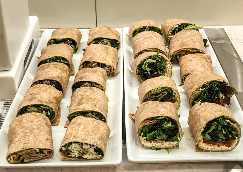 Two trays of mozzarella caprese wraps are placed side by side on a countertop.