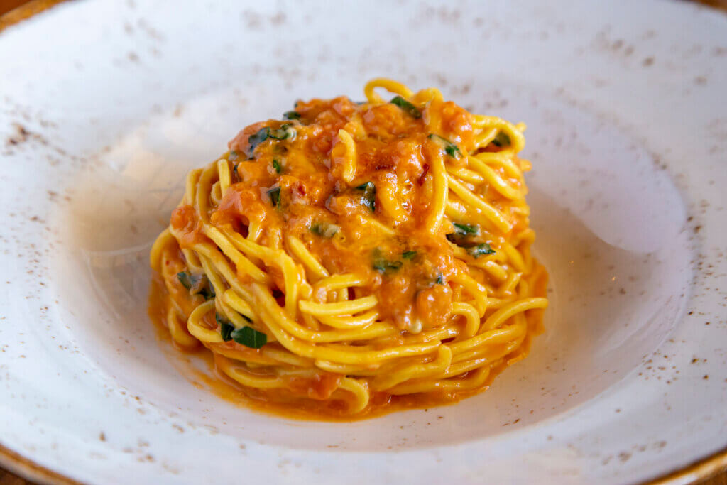 Spaghetti coiled into a neat nest and topped with red sauce is served in a bowl.