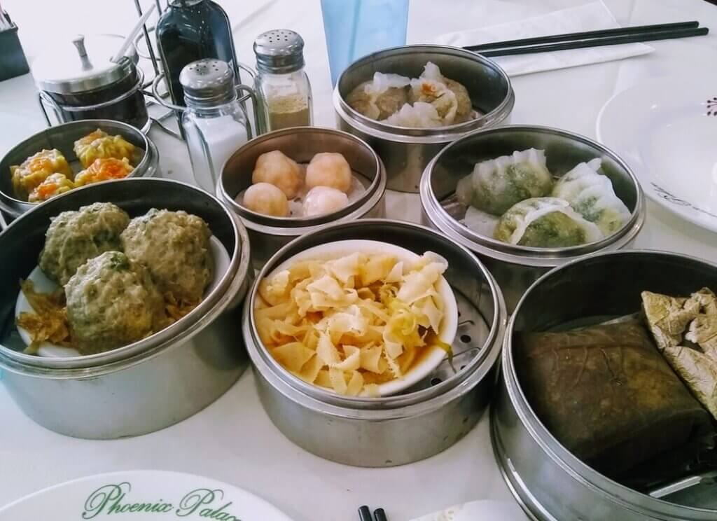 Many dishes of dim sum in steamers such as shrimp dumpling, pork dumpling, beef meatballs, etc. fill a tabletop.