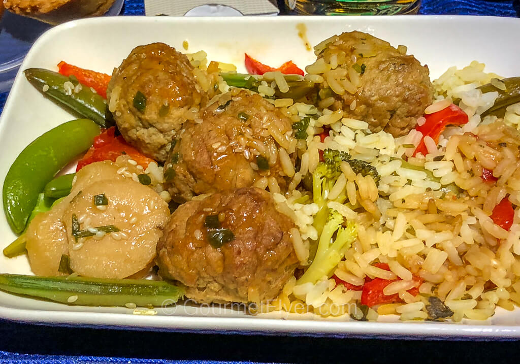 A plate of meatballs is served with rice, water chestnuts, and veggies.