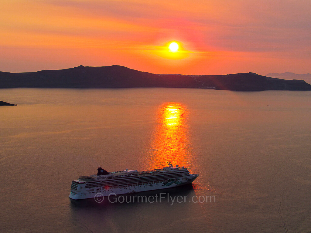 A cruise ships sailing into a gorgeous sunset in the backdrop.