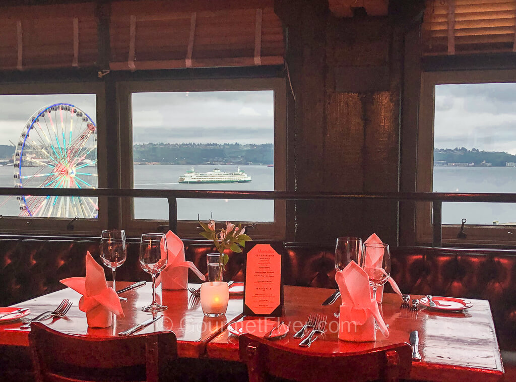 Seattle's waterfront with a Ferris wheel and a ferry is seen through the window of the restaurant.