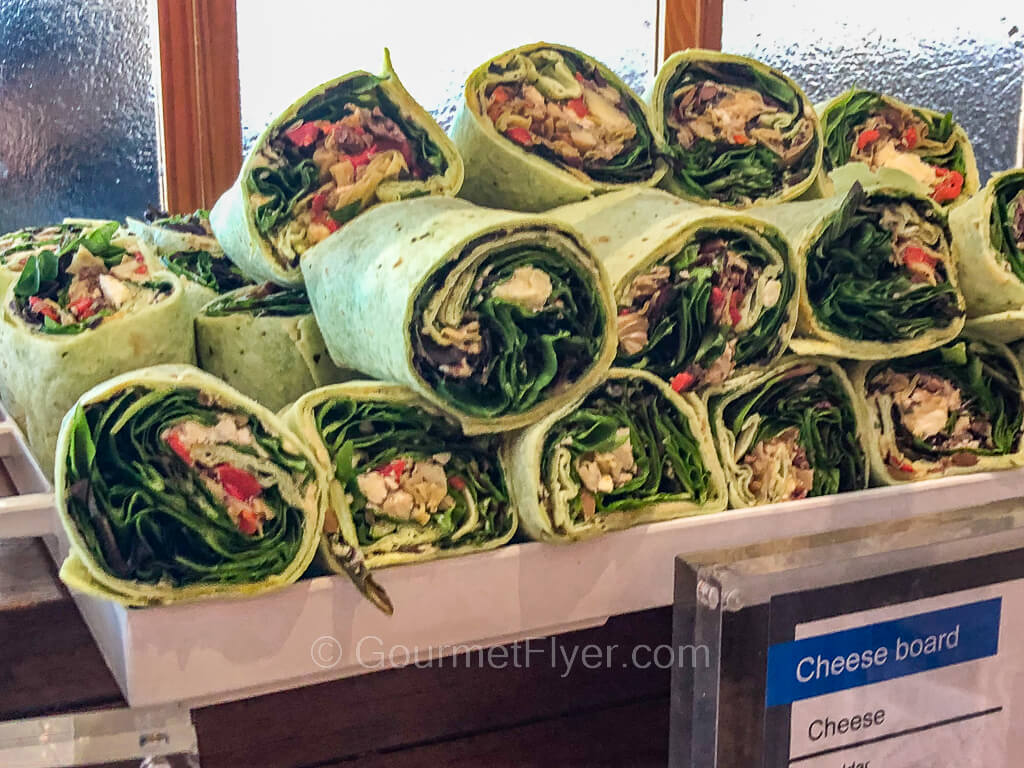 A stack of veggies wraps made with green flour tortillas are served on a platter.
