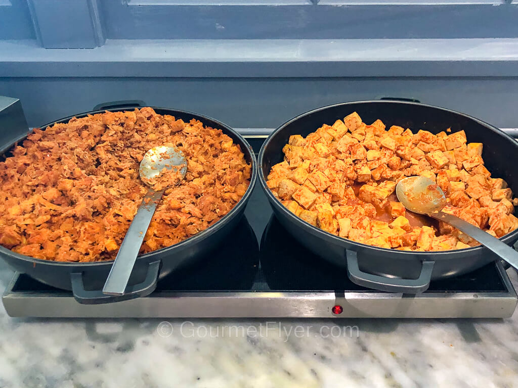 Two large bowls sit atop a counter with chicken on the left and tofu on the right.