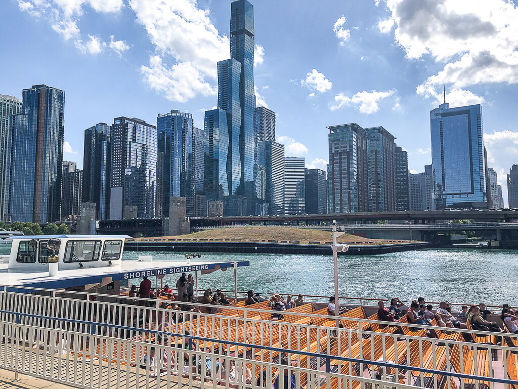 The open deck of a Chicago River cruise boat is half filled with passengers.