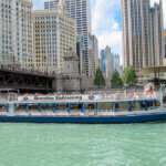 A Chicago architecture river cruise boat filled with tourists sails on the river.