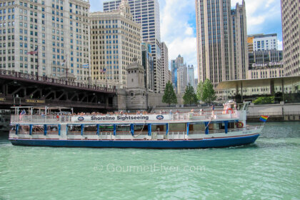 A Chicago architecture river cruise boat filled with tourists sails on the river.