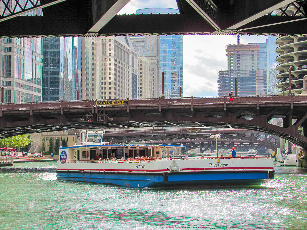 A Shoreline Sightseeing boat is sailing under the bridge labeled "State Street".