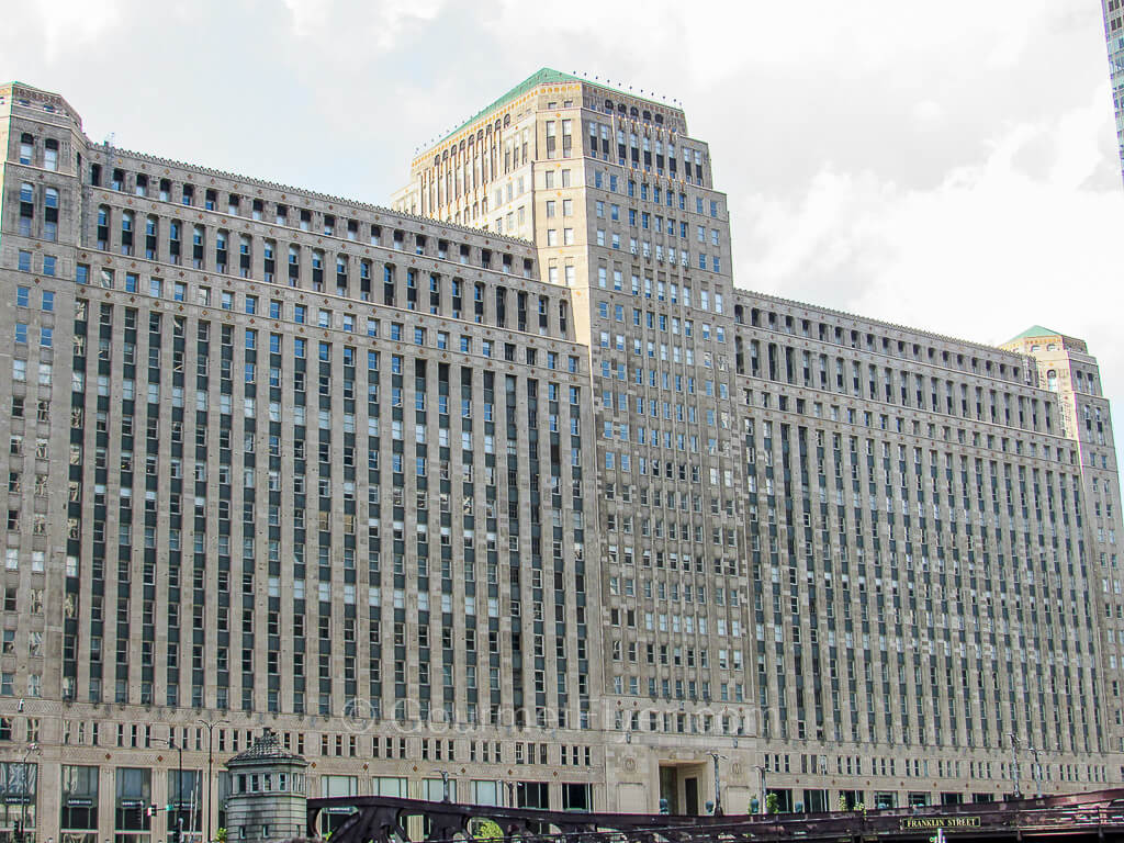 A massive building with an art deco style facade is separated into two wings by a tower in the center.