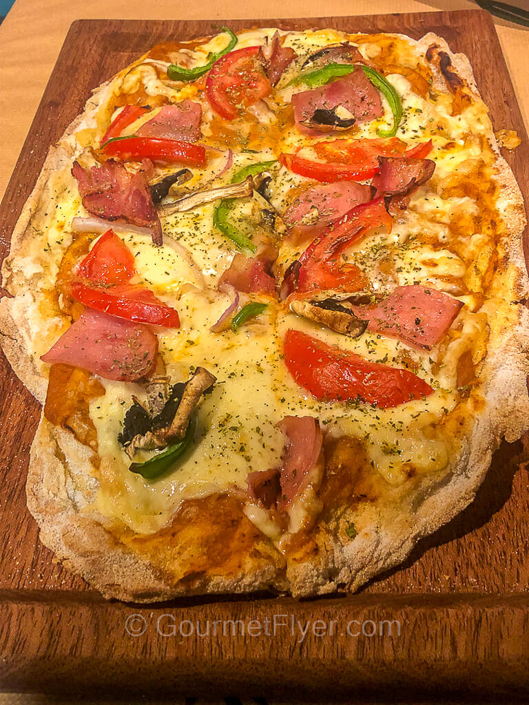 A flatbread with ham, mushrooms, tomatoes, and peppers.