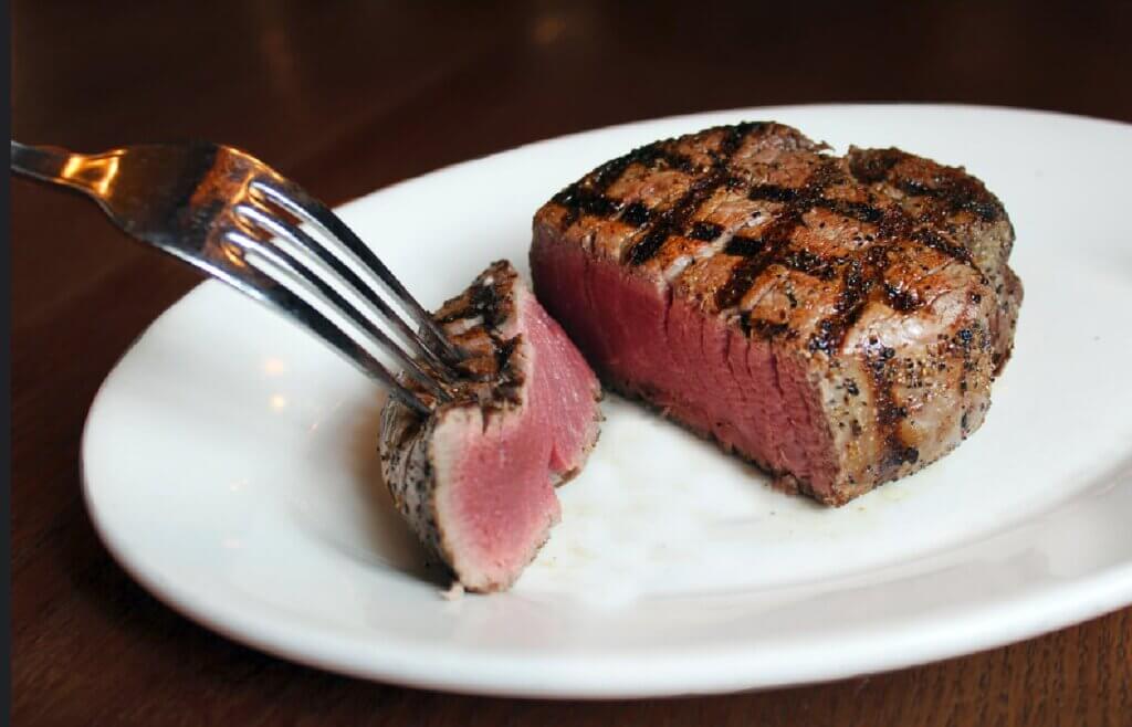 A filet mignon is cut open to show its medium rare interior.