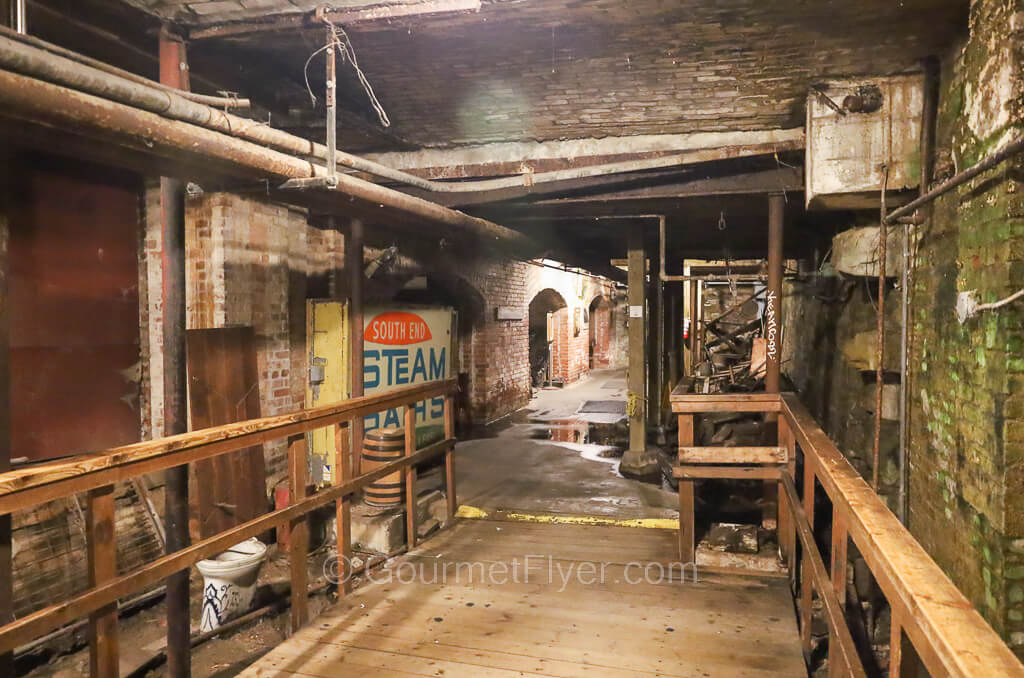 An underground passageway with wooden floor and stone walls.