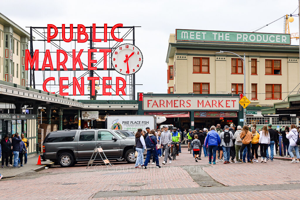 The large "Public Market Center" sign is lit up in red at the Pike Place Farmers Market.