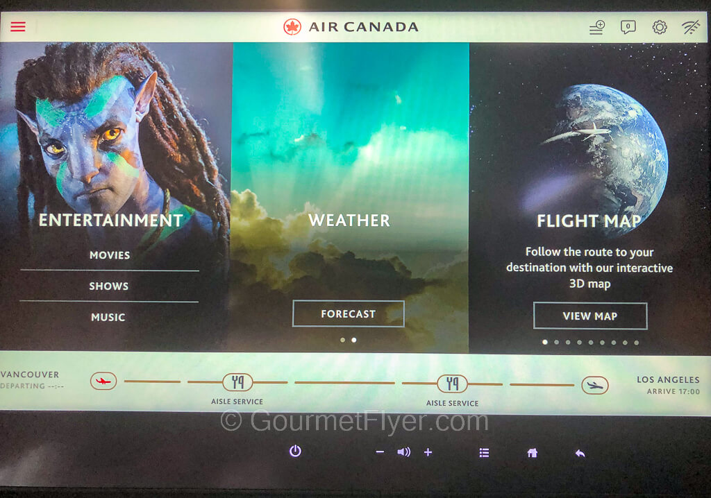 The TV screen of the in-flight entertainment unit features movies, weather, and an interactive map.