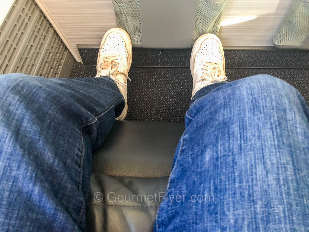 Someone wearing a pair of blue jeans and white tennis shoes demonstrates the use of the leg rest.