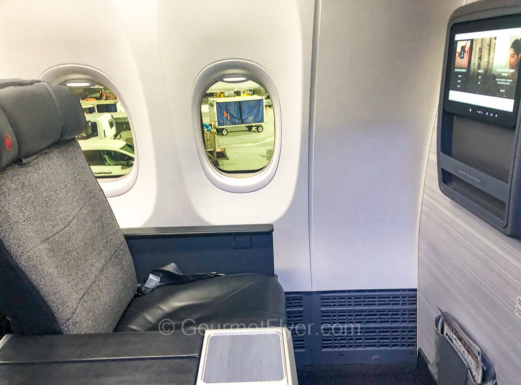 Bulkhead seat 1A of Air Canada Business Class has one and a half windows and plenty of space between the TV screen.