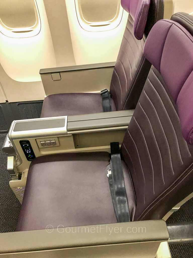 Two purple United Premium Plus seats on the right side of the plane, with the two window shades closed.