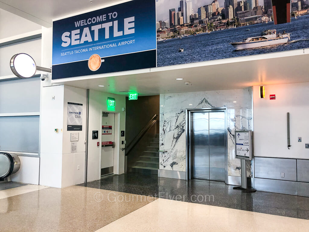 At the end of a moving walkway is an elevator with a small United Club sign.