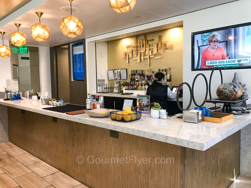 A female bartender is working behind a bar with a large counter but no bar stools.