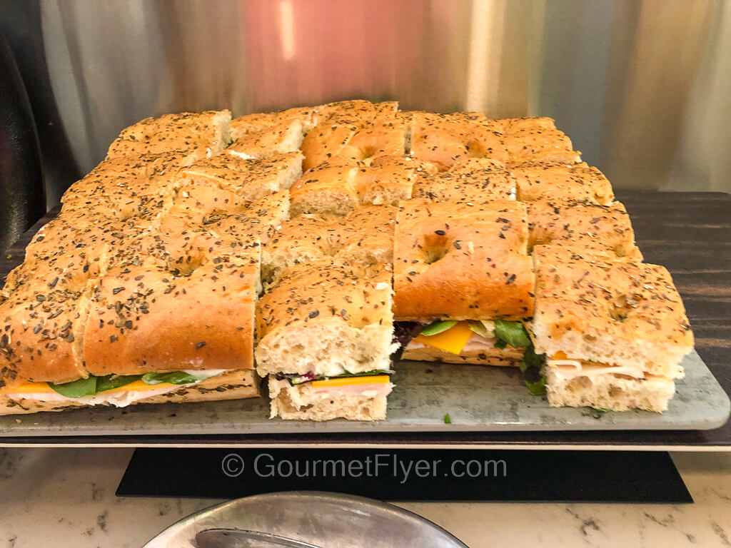 A large platter of cut up sub sandwiches made with turkey and cheese.