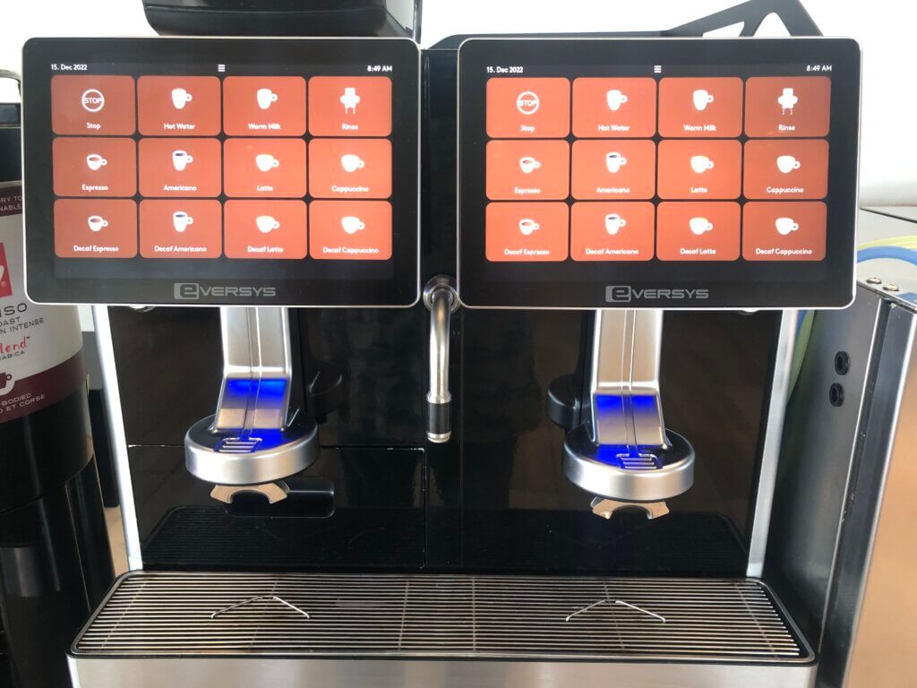 Two espresso machines with brown touchscreen buttons are placed next to each other.