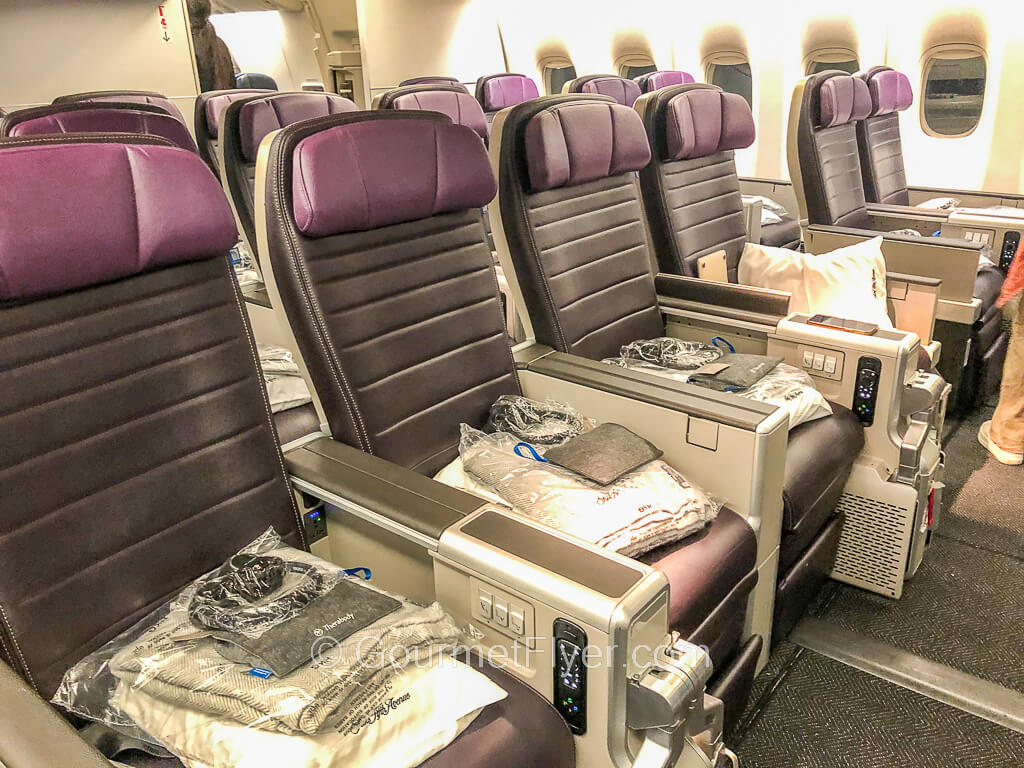 Review of United's Premium Plus between SFO and HKG features the bulkhead row of the purple seats with amenities and blankets placed on them.
