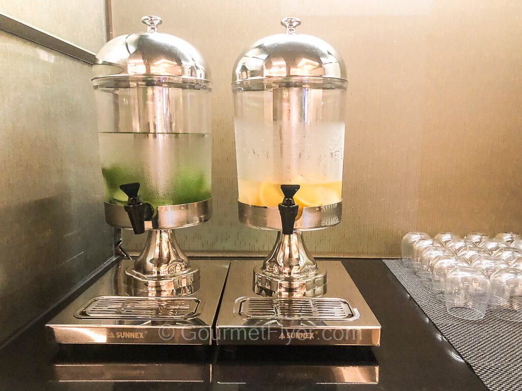 Two tubs of water sit atop a countertop, cucumber on the left and citrus on the right.