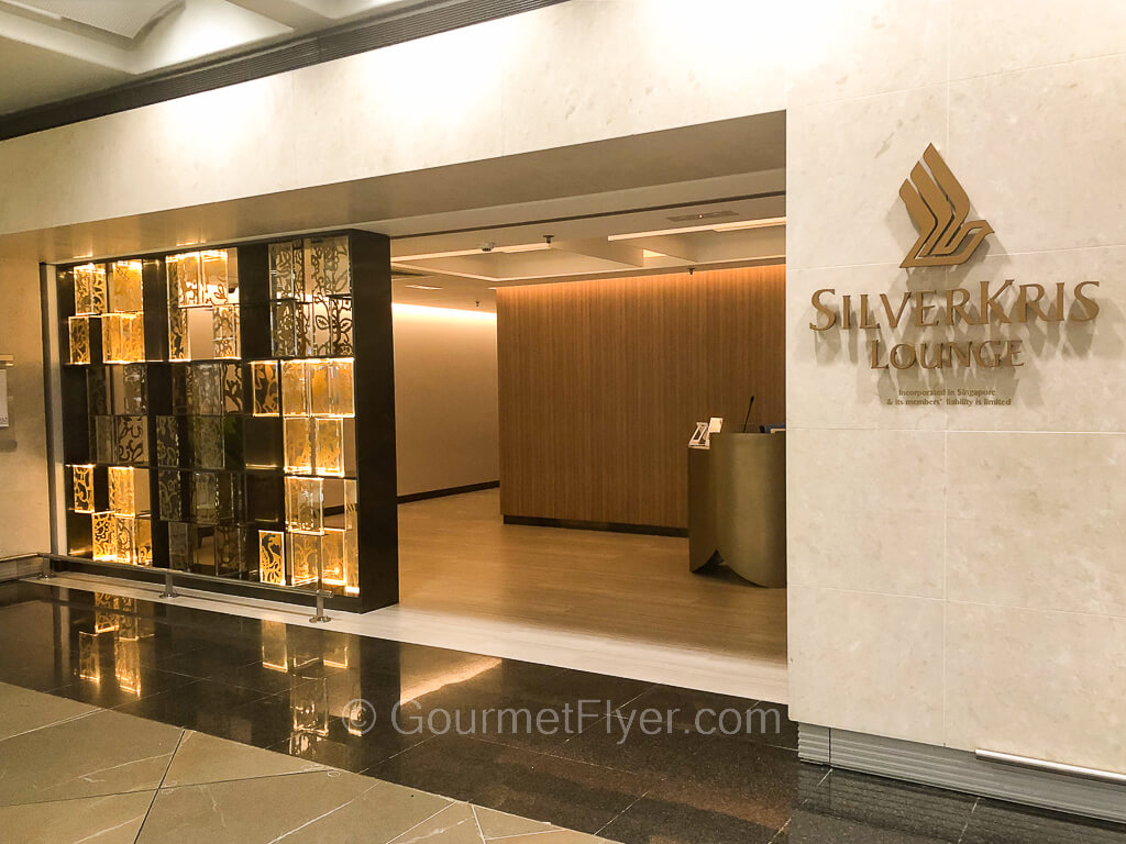 Review of the SilverKris Lounge features its grand entrance with the airlines' logo in gold on a marble wall.