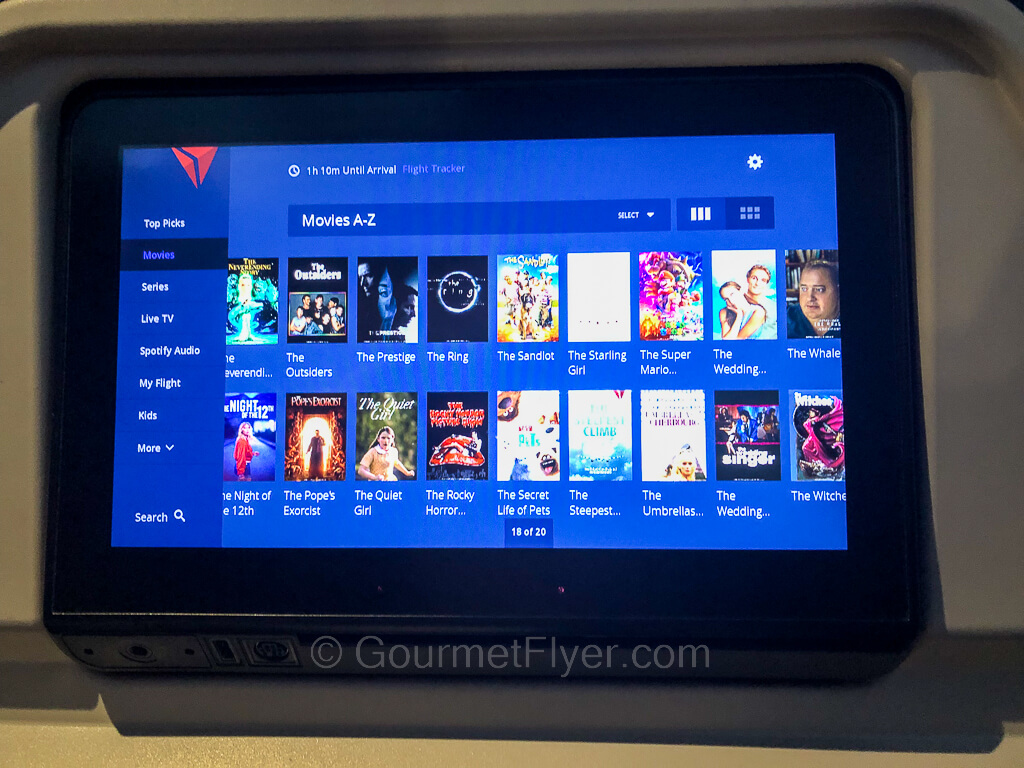 A seat-back entertainment screen shows icons of many movies in a blue background.