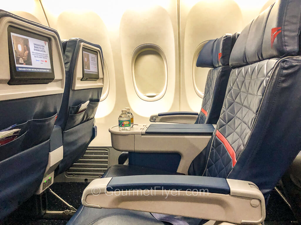 Two first-class seats in blue leather with Delta's logo are on the right hand side of the plane.