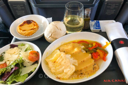 Review of Air Canada's Premium Economy class features a dinner tray with chicken and potatoes, salad, and dessert.