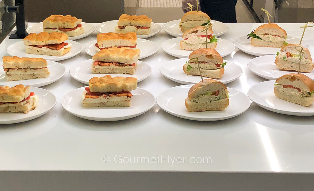 Plates of pre-cut sandwiches are placed on a countertop.