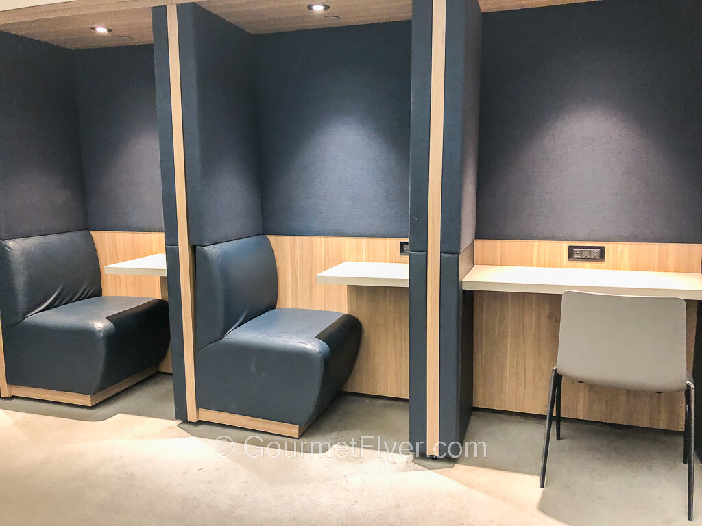 Three single cubicle like booths are equipped with a desk, chair, and power outlers.