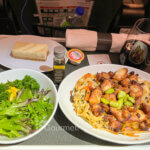 Review of Air Canada's Premium Economy features a dinner tray with a plate of chicken meat, a green salad, and dessert.