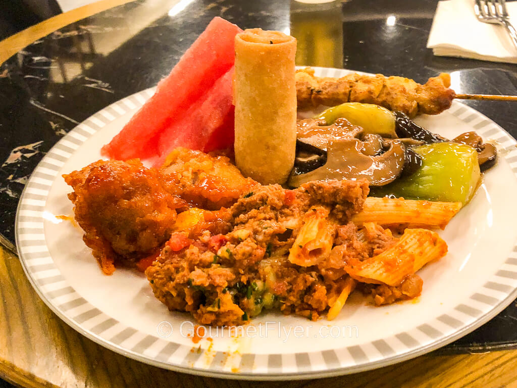 A plate with many different food items on it, including meat, pasta, and vegetables.
