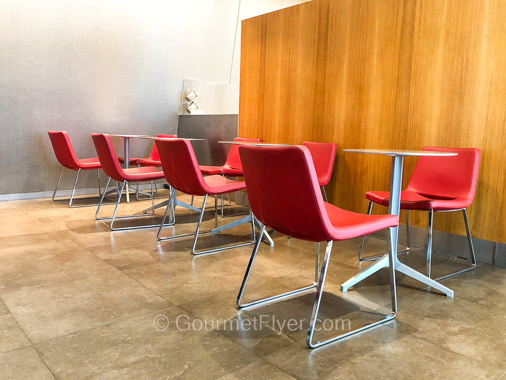 Four round dining tables are each accompanied by two stylish looking red chairs.