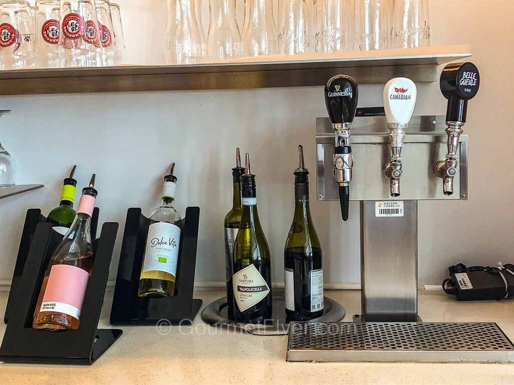 Several bottles of wines are on the left on a counter while a draft beer machine is on the right.