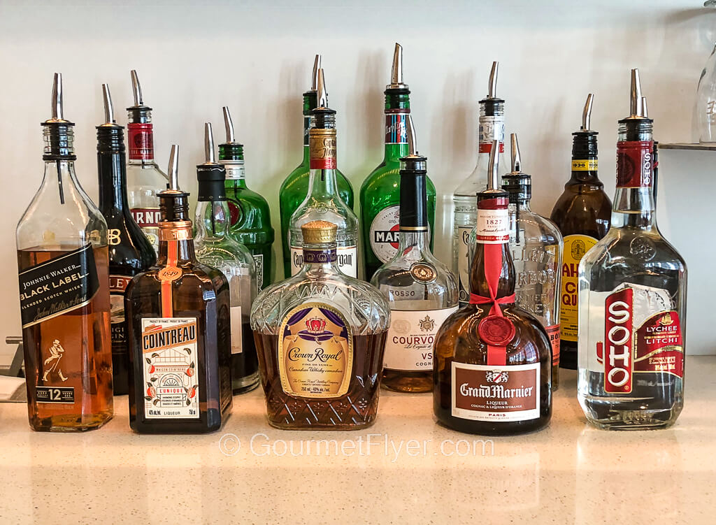 Many different bottles of liquors and spirits of all kinds are displayed on top of a counter.
