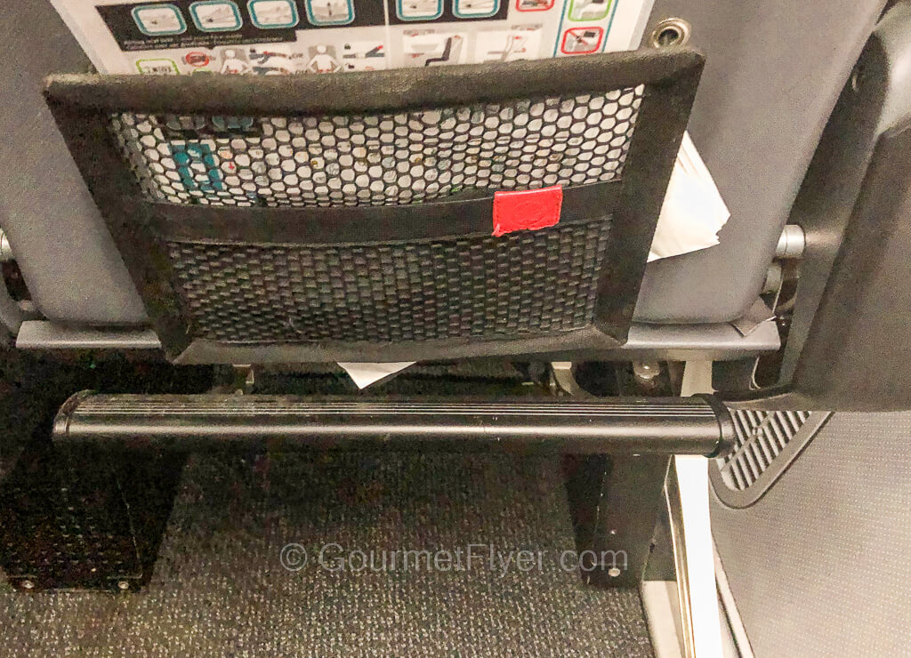 The footrest of an airplane seat is completely tilted to its uppermost position.