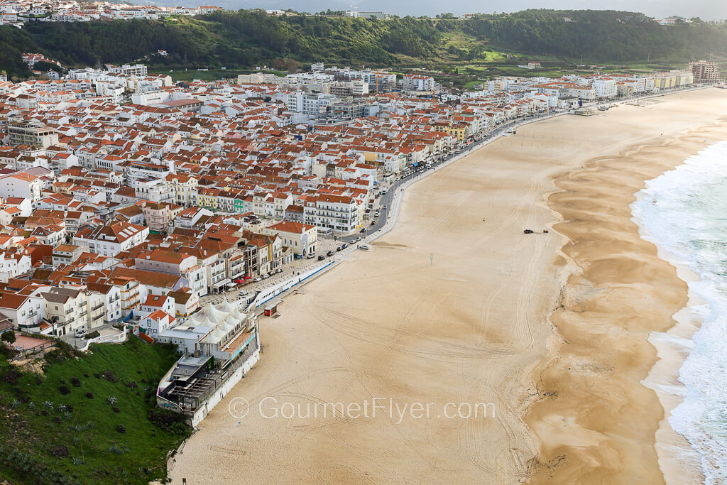 The long sandy beach of Nazare is empty of surfers on a day without waves.