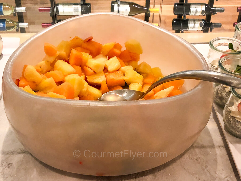 A bowl of cut fruits containing pineapple and melons.