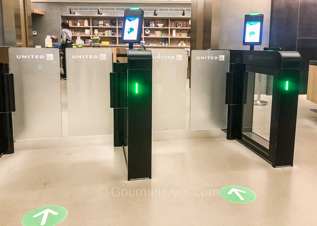 Two automated entry gates are equipped with a green light, a scanner, and a screen with instructions.