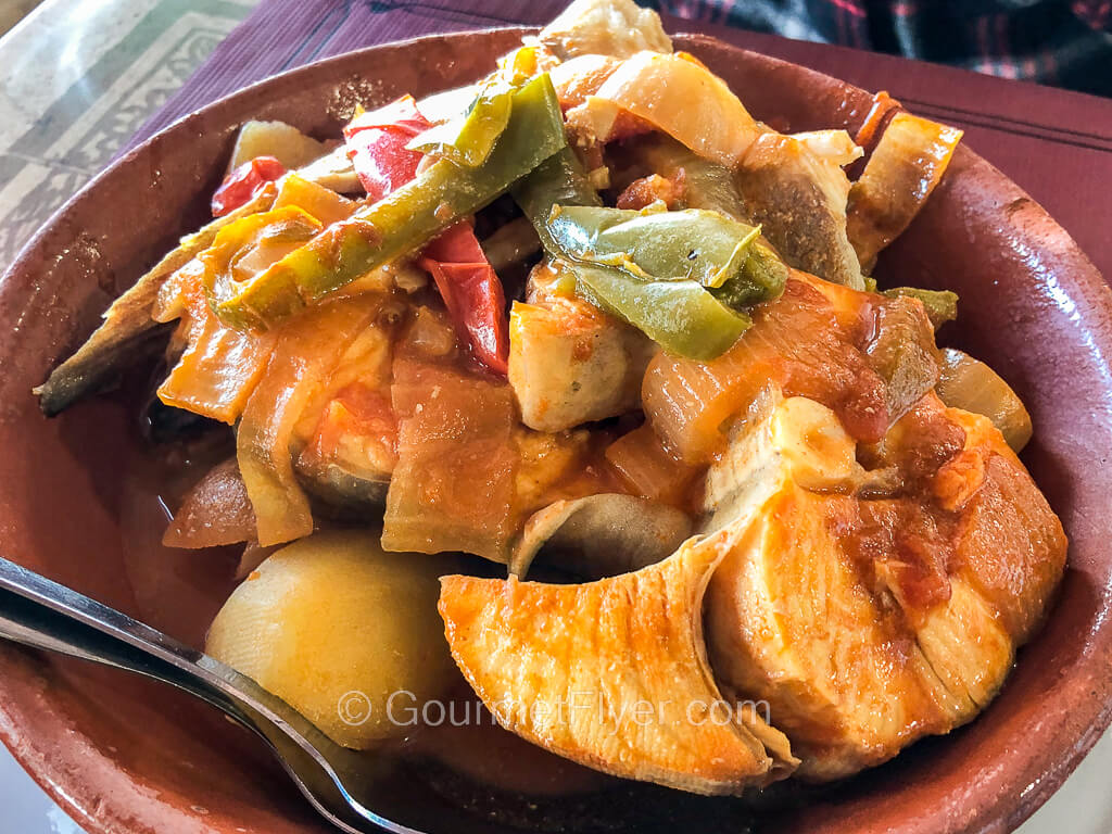 A bowl of fish stew with large chunks of fish filets and a blend of vegetables.