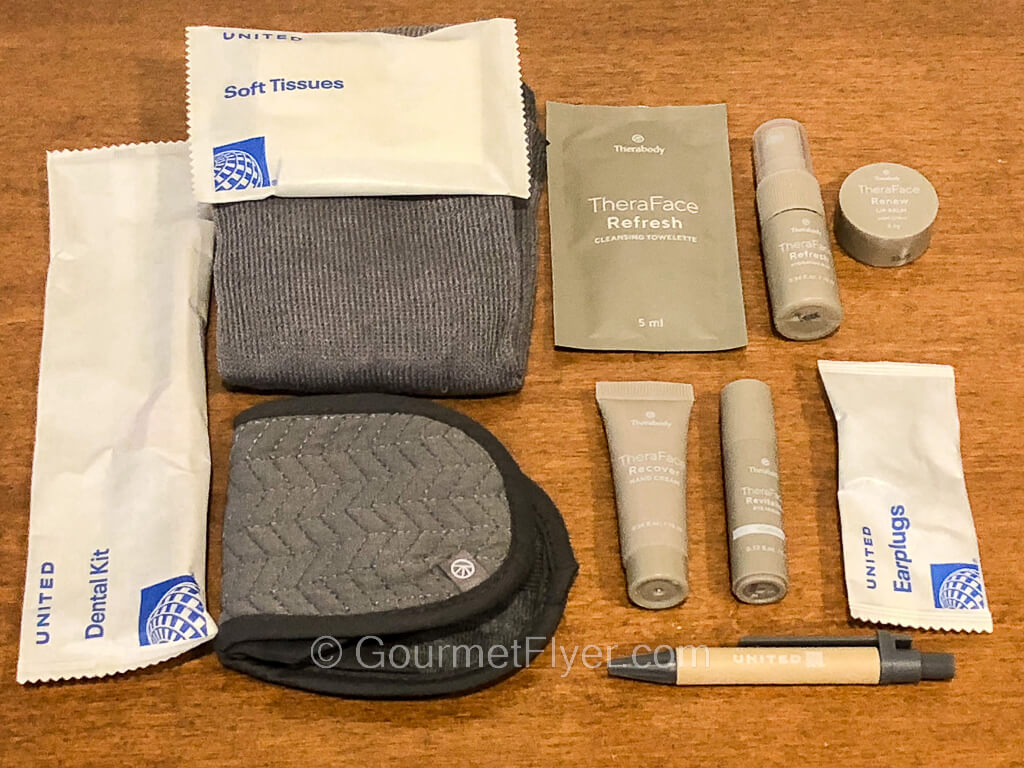 The contents of an amenity kit are taken out of the bag and spread out on a table.