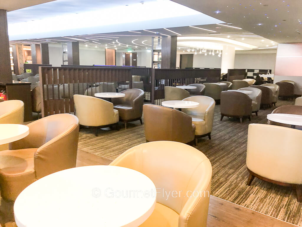 A bright and airy dining room is set up with round dining tables paired with leather lounge chairs.