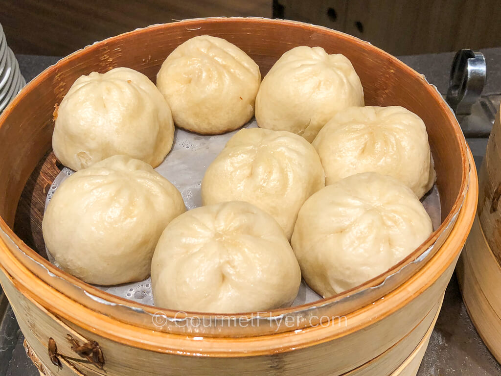 A bamboo steamer is filled with buns that appear to have been steamed.
