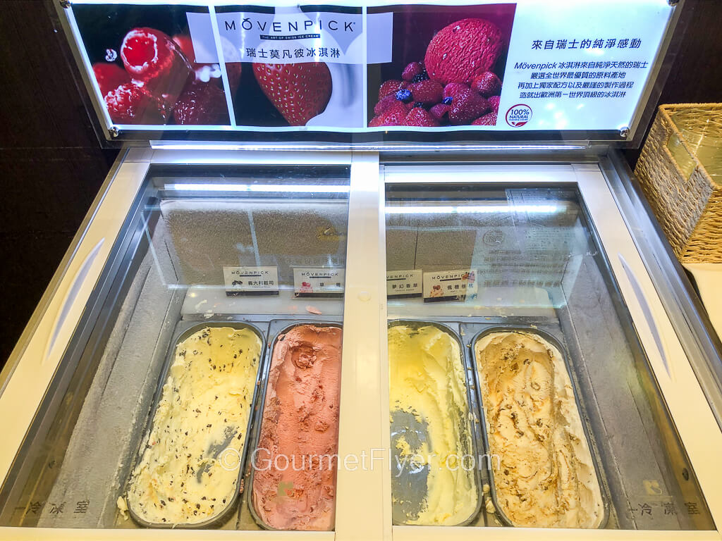 A refrigerated compartment with a glass door on top contains four different flavors of ice cream.
